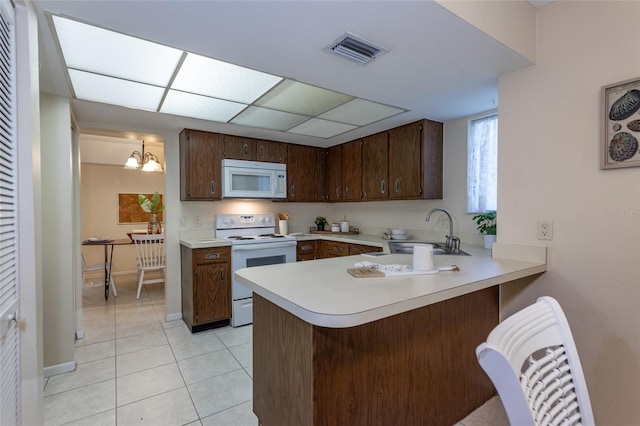 11 Surrey Ct Unit 11, Palm Coast, FL 32137 - kitchen with white appliances, light countertops, a peninsula, light tile patterned flooring, and dark brown cabinets
