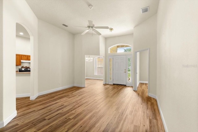1707 Southern Belle Ln, Port Orange, FL 32128 - foyer entrance featuring light wood-style floors, a ceiling fan, arched walkways, a chandelier, and a textured ceiling