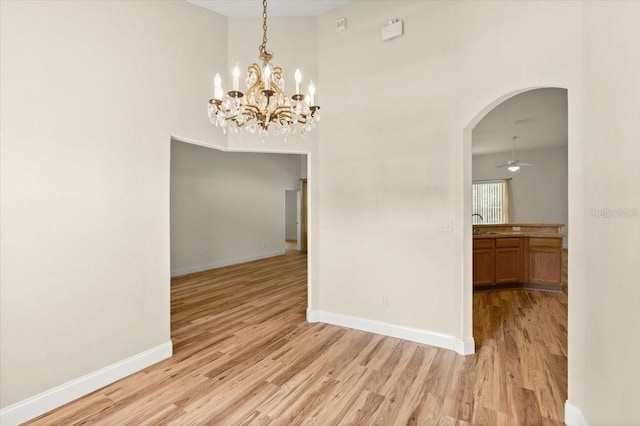 1707 Southern Belle Ln, Port Orange, FL 32128 - unfurnished dining area with arched walkways, light wood finished floors, a towering ceiling, a chandelier, and a ceiling fan