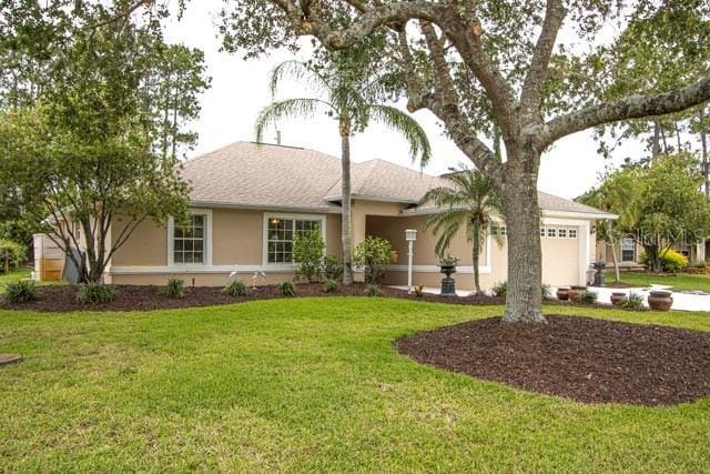 9 Empress Ln, Palm Coast, FL 32164 - single story home featuring an attached garage, stucco siding, a front lawn, and driveway