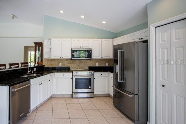 9 Empress Ln, Palm Coast, FL 32164 - kitchen with stainless steel appliances, vaulted ceiling, white cabinets, tasteful backsplash, and a peninsula