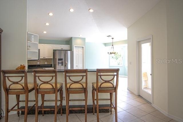 9 Empress Ln, Palm Coast, FL 32164 - kitchen with stainless steel fridge, a peninsula, recessed lighting, dark countertops, and white cabinets