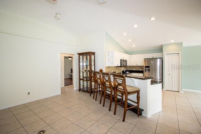 9 Empress Ln, Palm Coast, FL 32164 - kitchen with appliances with stainless steel finishes, dark countertops, light tile patterned floors, backsplash, and a peninsula