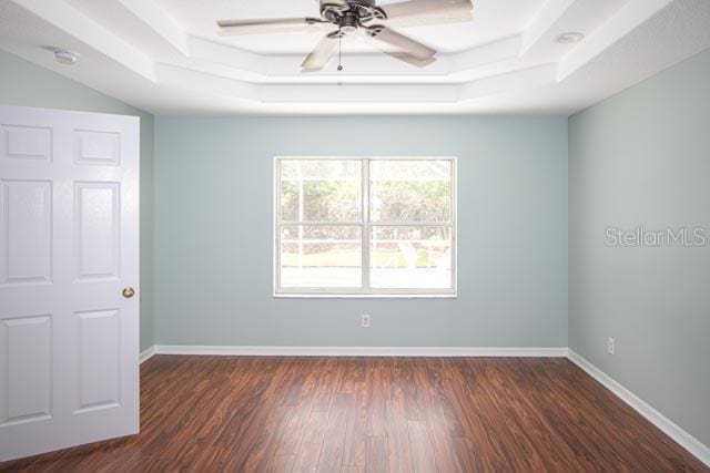 9 Empress Ln, Palm Coast, FL 32164 - unfurnished room featuring a raised ceiling, dark wood finished floors, ceiling fan, and a smoke detector