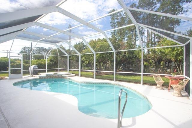 9 Empress Ln, Palm Coast, FL 32164 - outdoor pool with a patio area, a hot tub, and a lanai