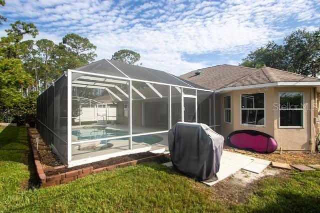 9 Empress Ln, Palm Coast, FL 32164 - back of property featuring an outdoor pool, a patio area, glass enclosure, and stucco siding