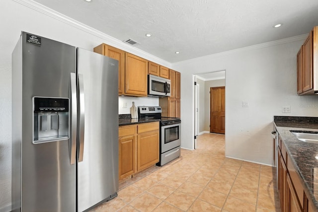 1146 Riverside Dr, Daytona Beach, FL 32117 - kitchen featuring stainless steel appliances, dark stone counters, brown cabinetry, recessed lighting, and crown molding