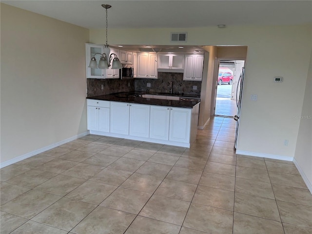 32 S Ocean Palm Villa Dr S Unit 320, Flagler Beach, FL 32136 - kitchen featuring stainless steel microwave, backsplash, light tile patterned floors, a peninsula, and hanging light fixtures
