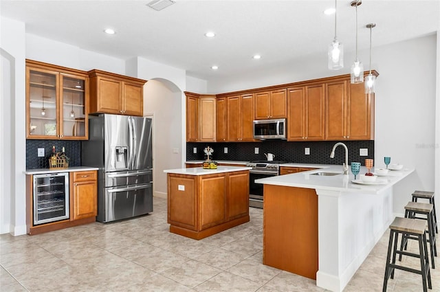 15 Long Pl, Palm Coast, FL 32137 - kitchen with stainless steel appliances, wine cooler, brown cabinetry, a peninsula, and decorative backsplash