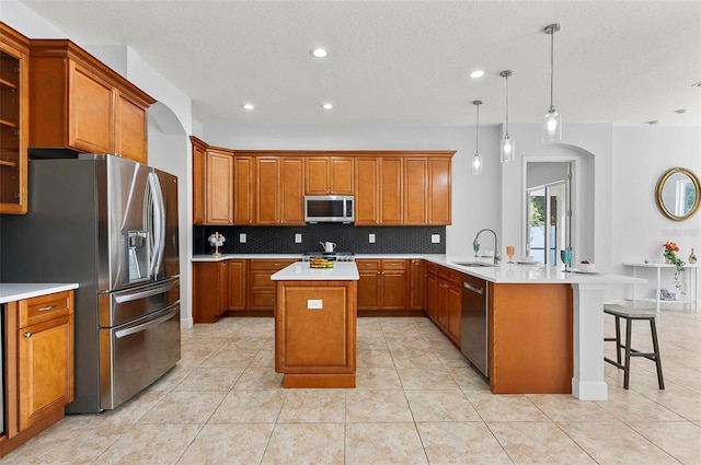 15 Long Pl, Palm Coast, FL 32137 - kitchen with appliances with stainless steel finishes, a peninsula, brown cabinets, tasteful backsplash, and recessed lighting