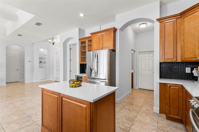 15 Long Pl, Palm Coast, FL 32137 - kitchen with appliances with stainless steel finishes, arched walkways, brown cabinets, tasteful backsplash, and a textured ceiling