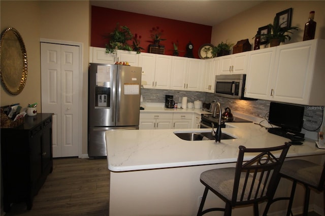 07 Gaston Pl, Palm Coast, FL 32164 - kitchen with appliances with stainless steel finishes, a peninsula, dark wood-style flooring, backsplash, and white cabinetry