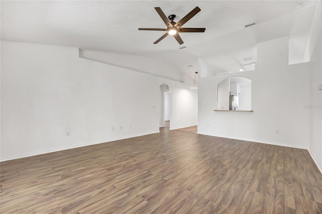 112 Ulaturn Trl, Palm Coast, FL 32164 - unfurnished living room with a ceiling fan, wood finished floors, arched walkways, a textured ceiling, and vaulted ceiling