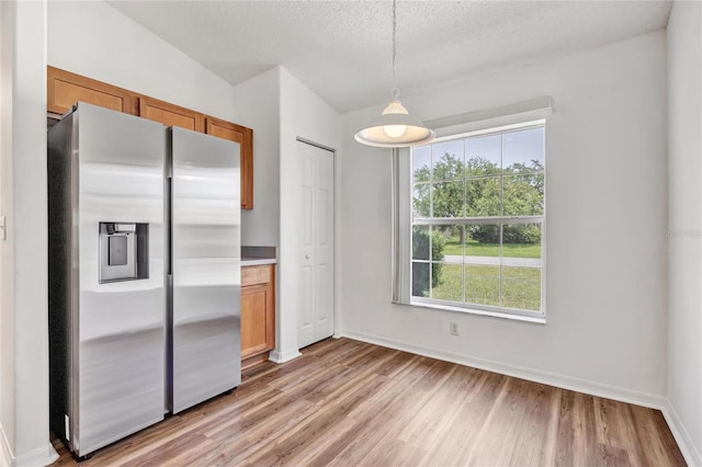 112 Ulaturn Trl, Palm Coast, FL 32164 - kitchen with stainless steel fridge with ice dispenser, light wood-type flooring, brown cabinets, decorative light fixtures, and a textured ceiling