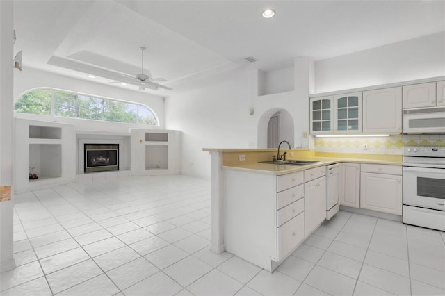 16 Birchwood Pl, Palm Coast, FL 32137 - kitchen with white appliances, a glass covered fireplace, a peninsula, light tile patterned flooring, and glass insert cabinets