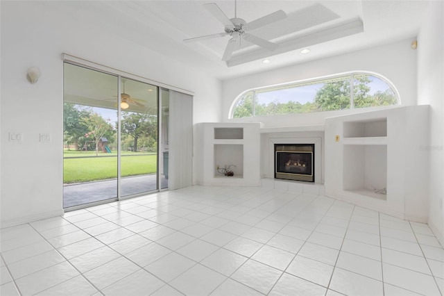 16 Birchwood Pl, Palm Coast, FL 32137 - unfurnished living room with a glass covered fireplace, a ceiling fan, a raised ceiling, recessed lighting, and tile patterned floors