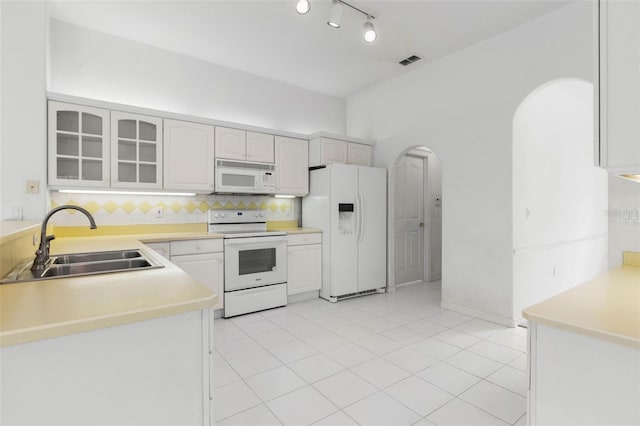 16 Birchwood Pl, Palm Coast, FL 32137 - kitchen with white appliances, arched walkways, backsplash, glass insert cabinets, and light countertops