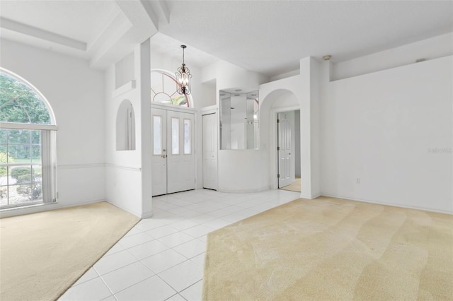 16 Birchwood Pl, Palm Coast, FL 32137 - entrance foyer with carpet flooring, tile patterned floors, a chandelier, and arched walkways