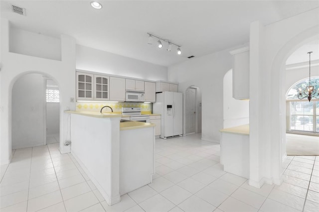 16 Birchwood Pl, Palm Coast, FL 32137 - kitchen with arched walkways, white appliances, light countertops, and glass insert cabinets