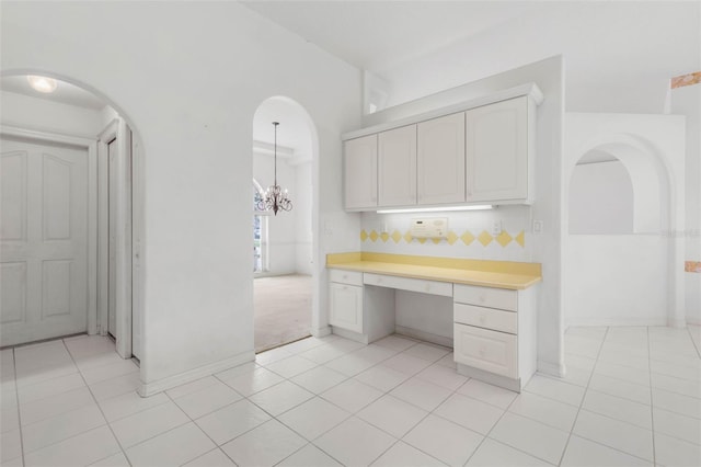 16 Birchwood Pl, Palm Coast, FL 32137 - kitchen with built in study area, arched walkways, light tile patterned floors, light countertops, and white cabinets
