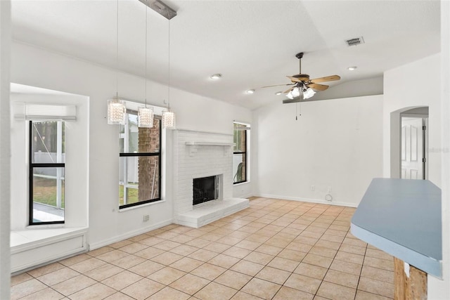 2790 Pelham Cir, Deltona, FL 32738 - unfurnished living room featuring ceiling fan, light tile patterned floors, a fireplace, vaulted ceiling, and arched walkways