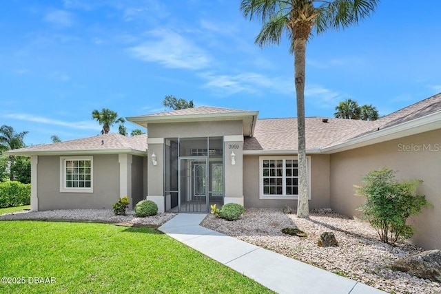 3959 S Chinook Ln, Ormond Beach, FL 32174 - view of front of property featuring stucco siding, a sunroom, a front yard, and roof with shingles