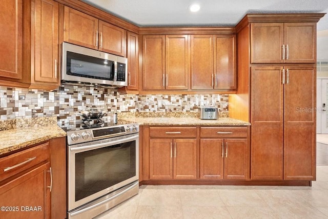 3959 S Chinook Ln, Ormond Beach, FL 32174 - kitchen with appliances with stainless steel finishes, brown cabinets, light stone countertops, backsplash, and recessed lighting