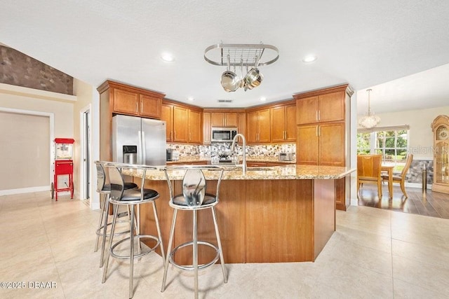 3959 S Chinook Ln, Ormond Beach, FL 32174 - kitchen with appliances with stainless steel finishes, tasteful backsplash, light stone counters, brown cabinetry, and recessed lighting