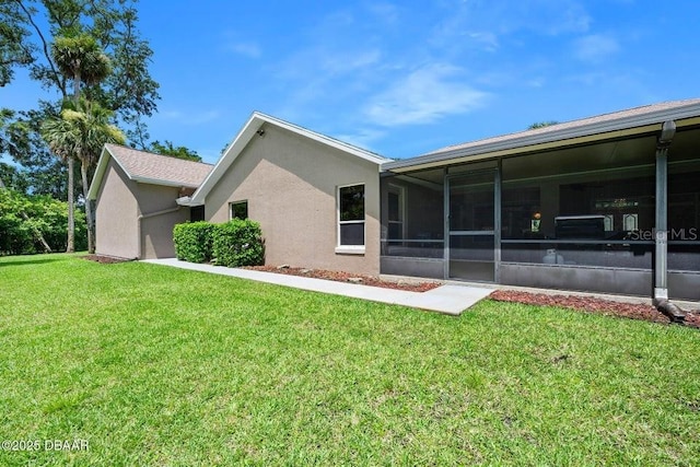 3959 S Chinook Ln, Ormond Beach, FL 32174 - rear view of house featuring a sunroom, a lawn, and stucco siding