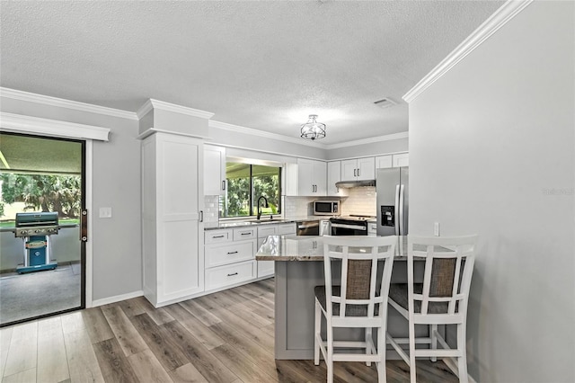 16 Courtney Pl, Palm Coast, FL 32137 - kitchen with a textured ceiling, stainless steel appliances, wood finished floors, tasteful backsplash, and a breakfast bar