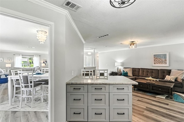 16 Courtney Pl, Palm Coast, FL 32137 - kitchen with open floor plan, ornamental molding, a textured ceiling, light wood-style floors, and light stone counters