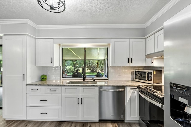 16 Courtney Pl, Palm Coast, FL 32137 - kitchen featuring stainless steel appliances, crown molding, a textured ceiling, white cabinetry, and light stone counters