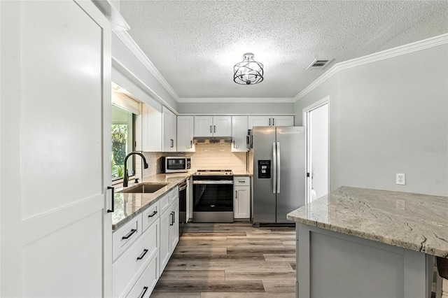 16 Courtney Pl, Palm Coast, FL 32137 - kitchen featuring appliances with stainless steel finishes, light wood finished floors, ornamental molding, light stone counters, and a textured ceiling