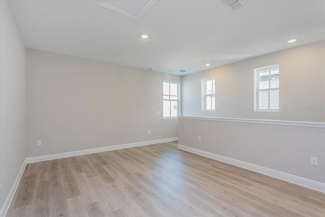 empty room with baseboards, visible vents, and light wood finished floors