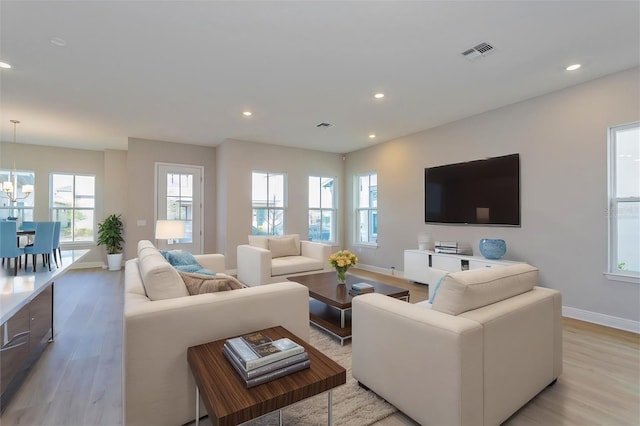 living room featuring light wood-type flooring, visible vents, an inviting chandelier, and recessed lighting