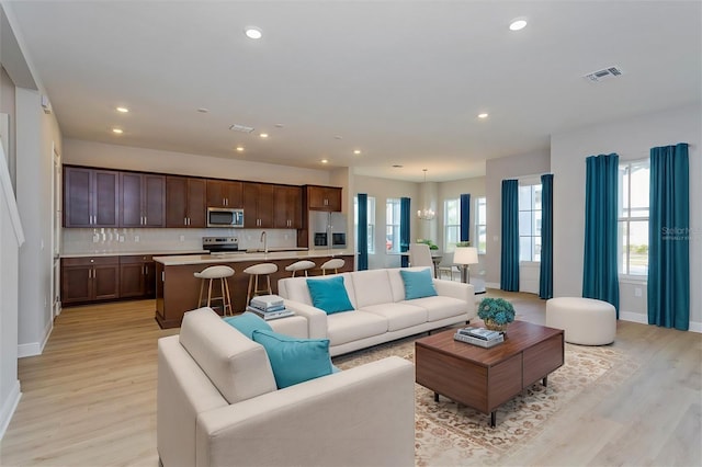 living area with light wood-style floors, recessed lighting, visible vents, and baseboards