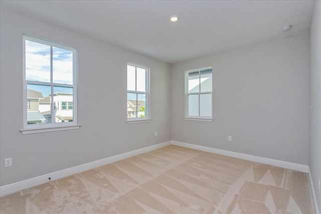 empty room featuring recessed lighting, light carpet, and baseboards