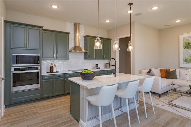 kitchen with a kitchen breakfast bar, stainless steel appliances, wall chimney range hood, tasteful backsplash, and pendant lighting