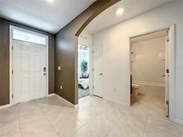 tiled entrance foyer featuring a textured ceiling and ceiling fan