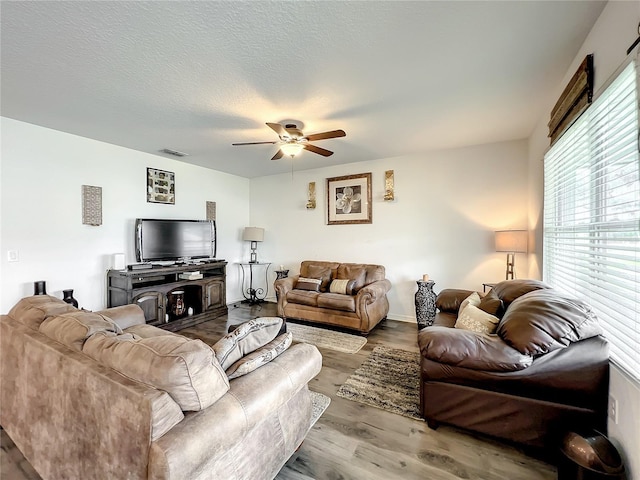 living room with a textured ceiling, ceiling fan, and hardwood / wood-style flooring