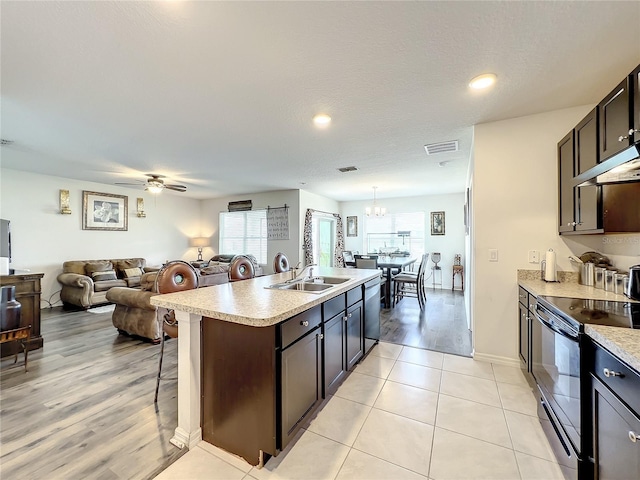 kitchen with sink, dark brown cabinets, black range with electric stovetop, decorative light fixtures, and ceiling fan with notable chandelier