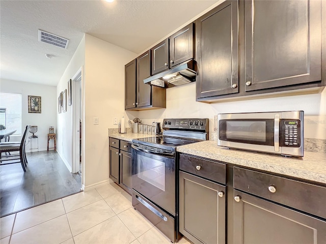 kitchen with range with electric stovetop, a textured ceiling, light tile flooring, and dark brown cabinetry