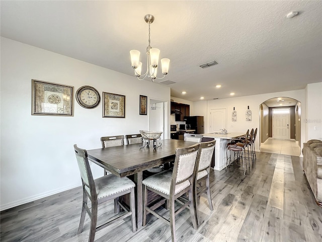 dining room with a textured ceiling, a chandelier, and dark hardwood / wood-style flooring