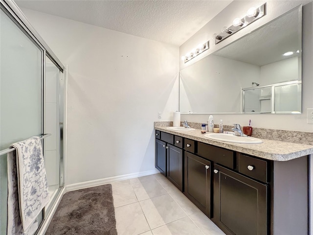 bathroom featuring a shower with door, tile floors, dual sinks, a textured ceiling, and large vanity