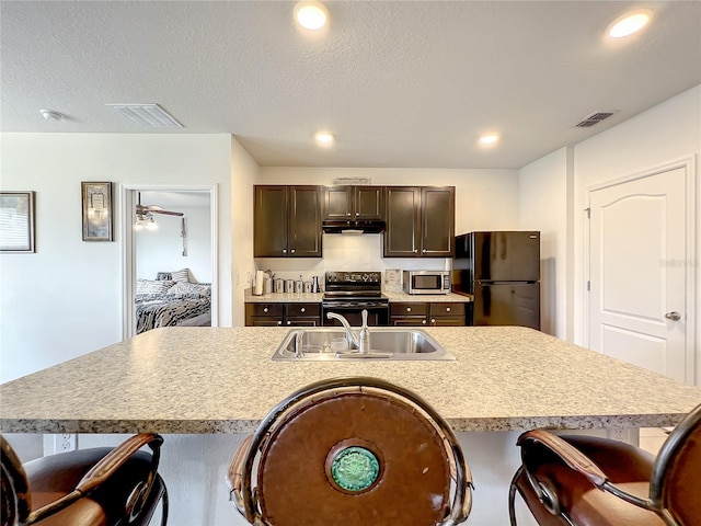 kitchen featuring range with electric cooktop, a center island with sink, and a kitchen breakfast bar