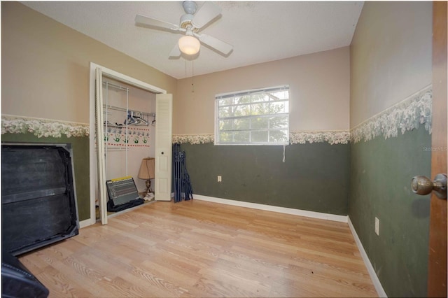 9701 E Warm Springs Ave, Coleman, FL 33521 - unfurnished bedroom featuring wood finished floors, a closet, a wainscoted wall, and ceiling fan