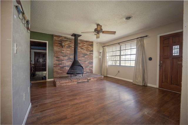 9701 E Warm Springs Ave, Coleman, FL 33521 - unfurnished living room with a wood stove, ceiling fan, a textured ceiling, and wood finished floors