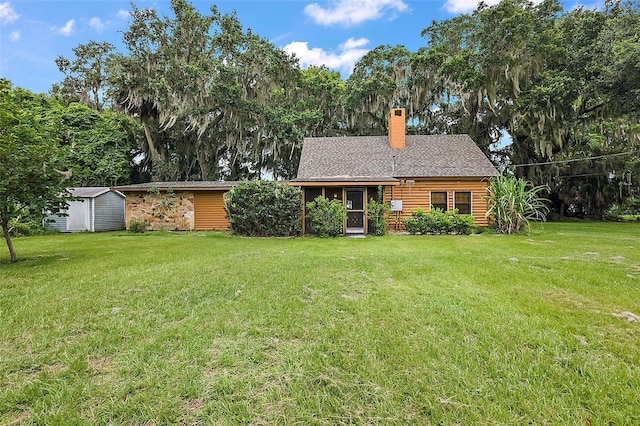 back of house with a lawn and a storage shed