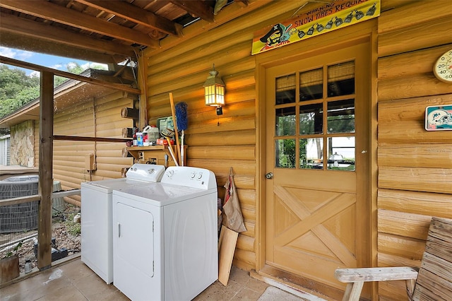 washroom with a wealth of natural light, washing machine and dryer, and log walls