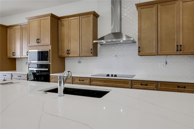 kitchen featuring sink, black appliances, wall chimney exhaust hood, and light stone countertops